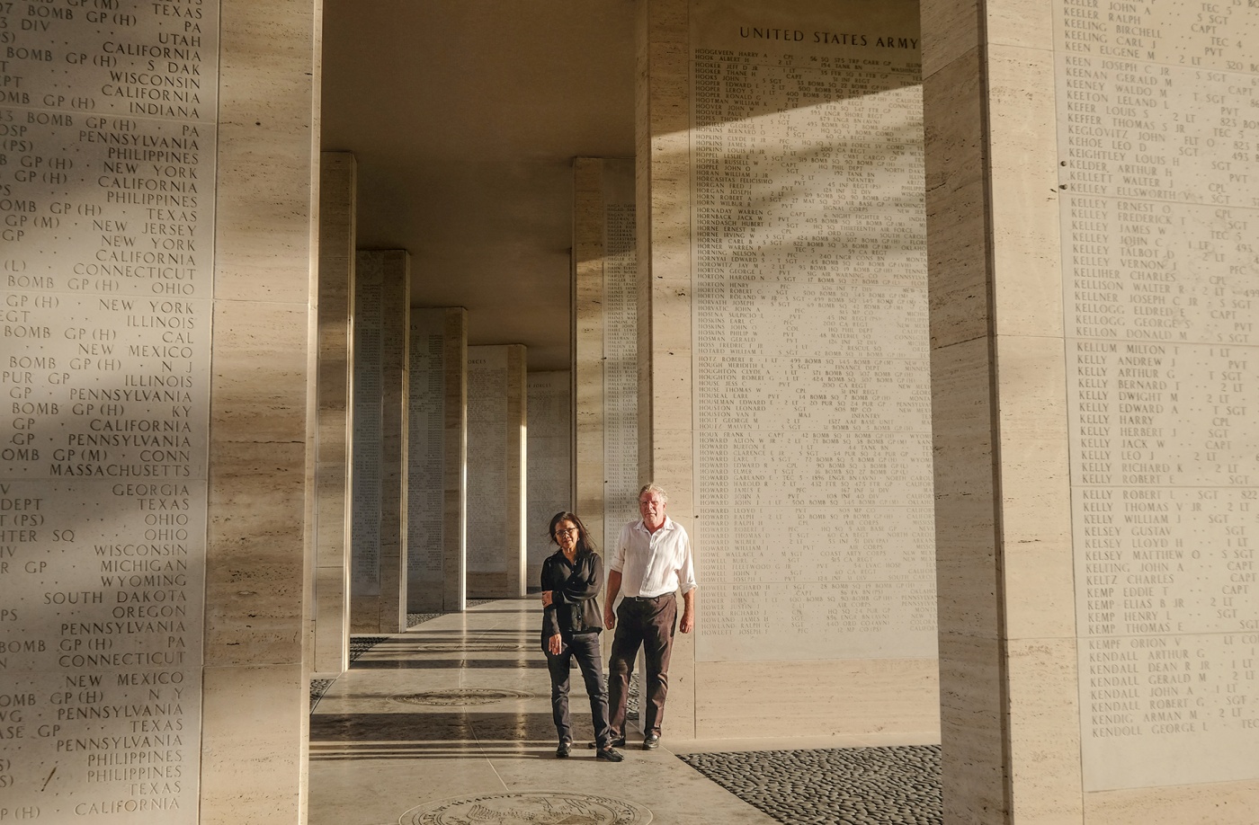 Mark Gillen &rsquo;77 and his wife, Delmafe Festin, standing at the Manila American Cemetery between stone columns